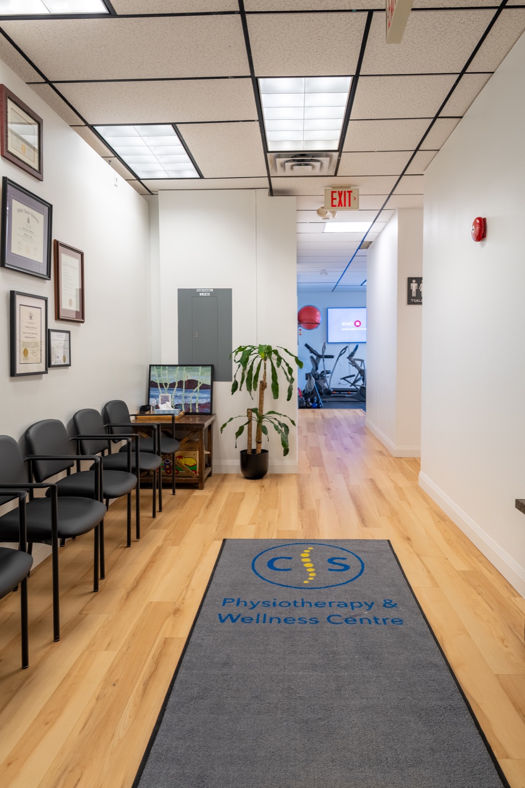 Welcoming entrance with seating and framed credentials, leading toward the rehab gym